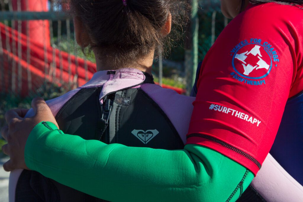A Waves For Change employee with one arm around the shoulders of a child