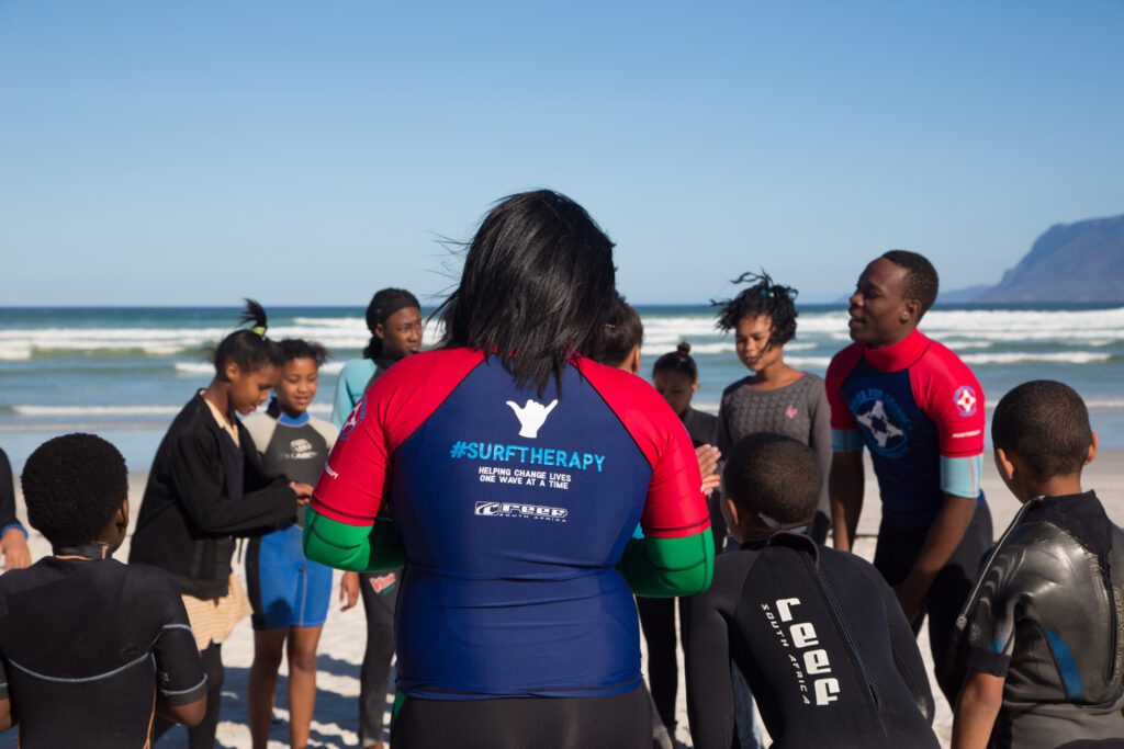 Waves For Change employees and participants in a circle on the beach