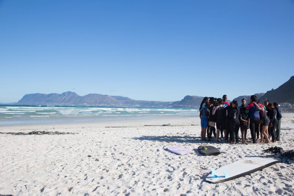 Waves For Change employees and participants standing in a circle on the beach